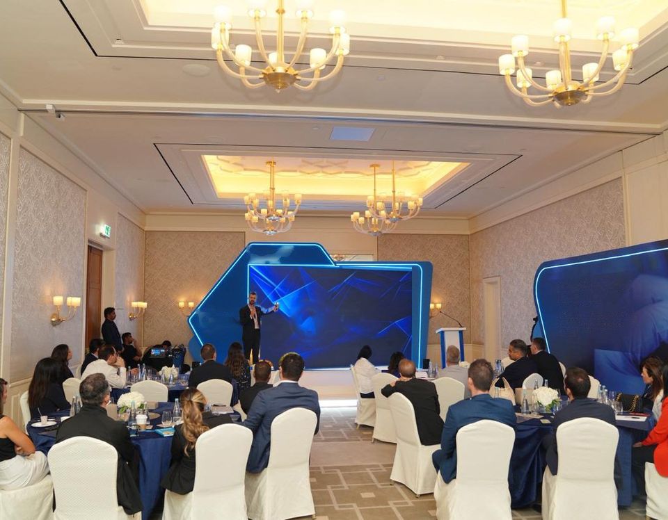 Guests seated at round tables facing the LED stage
