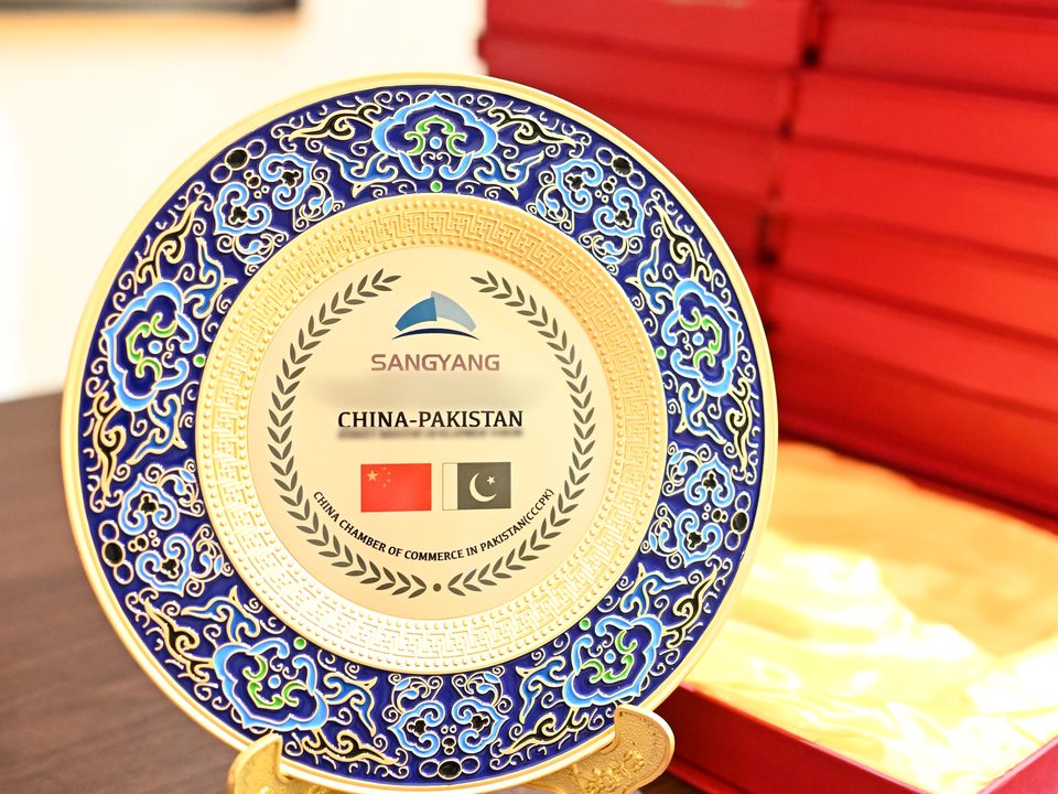 Commemorative plate on a stand beside red presentation boxes