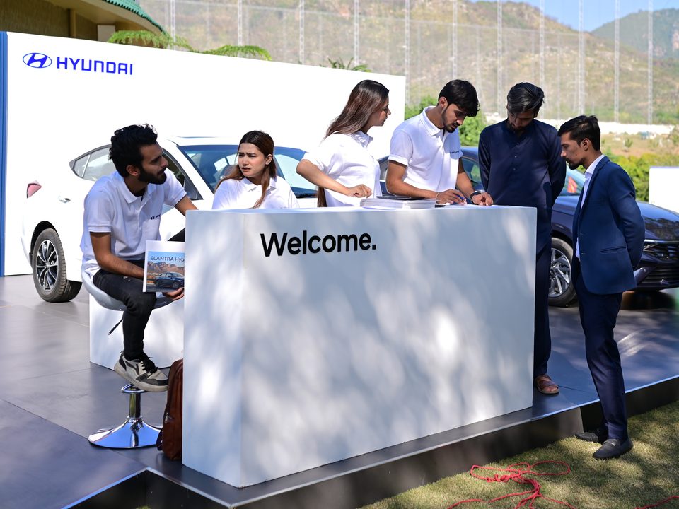 Welcome counter on a car display platform, staff talking with guests