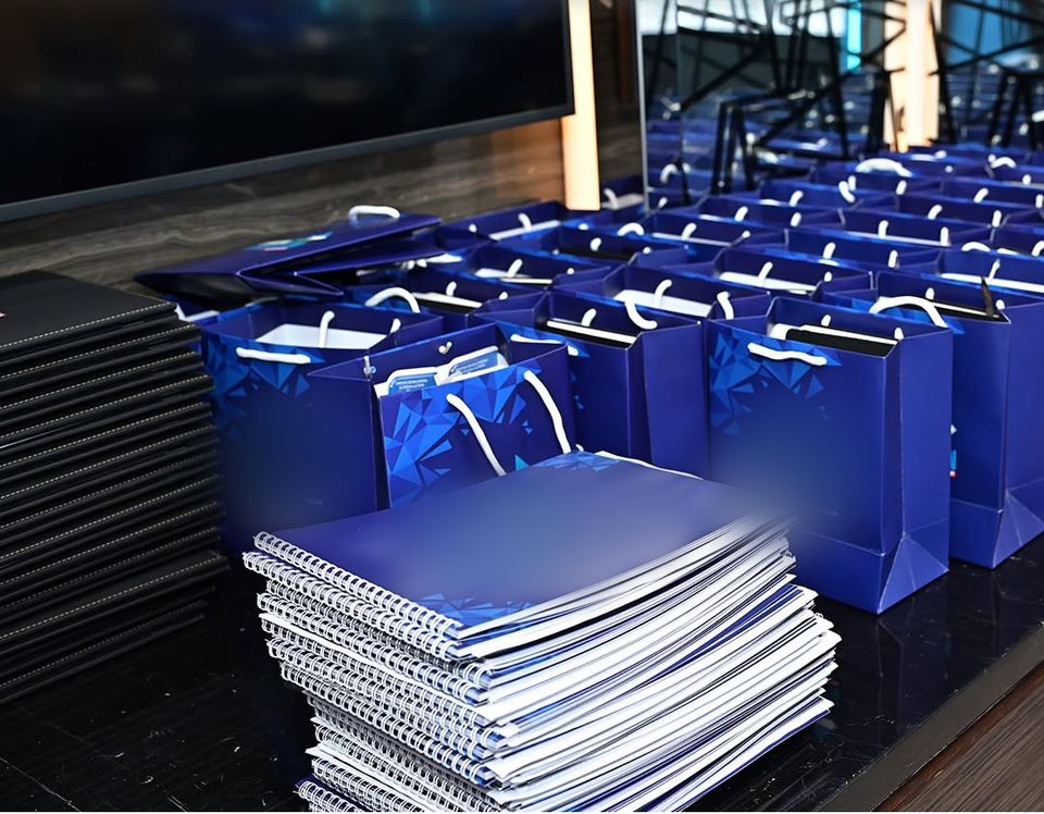 Guest gift bags and spiral-bound packs laid out on a table